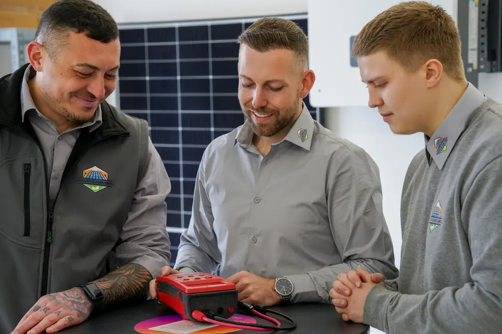 Drei Mitarbeiter von Energietechnik Broll mit Prüfgerät und Prüfprotokoll