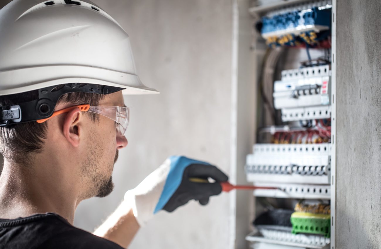 Man, an electrical technician working in a switchboard with fuses. Installation and connection of electrical equipment. Professional with tools in hand. concept of complex work, space for text. SSUCv3H4sIAAAAAAAEAI1Ry2rDMBC8F/oPRucYZMchdv+gh0LvoYe1tIlFFW3QoyWE/HslKyo6ld60M6vZnZ3b81PTsBmcEuyluaUq1krr4LwFr8hEmG8euEUj0dYISuXJKtA1OIMXi4EzRtAErRN8X0nmPPjg0KVhD0iAx1PUyOCvRN7okOumECsZf0SKvSNdNLJNxbgwJ+ZNOYFag0EKjhX+vvlD7NXIZDk5+b9gfnwU33BCI66rtcqyRY2QLR9yK/v89mjP9REgSEWV/y8SoFPDtlK6WCWUOVXfyC9rHuWboGC8TSuwYoNpogvMOoVxjJpY8AWci+2y4NUgEU9B52qOIb8aeKgyGTNLZbftu3EYdkPX7Uc+8h1nJWcSn0rWFnP0i4qUvVa4ShuwnostiGnfTv00tEOPuxYQx3bY81FwfpxG4PHw9x+hX0Y7sQIAAA==